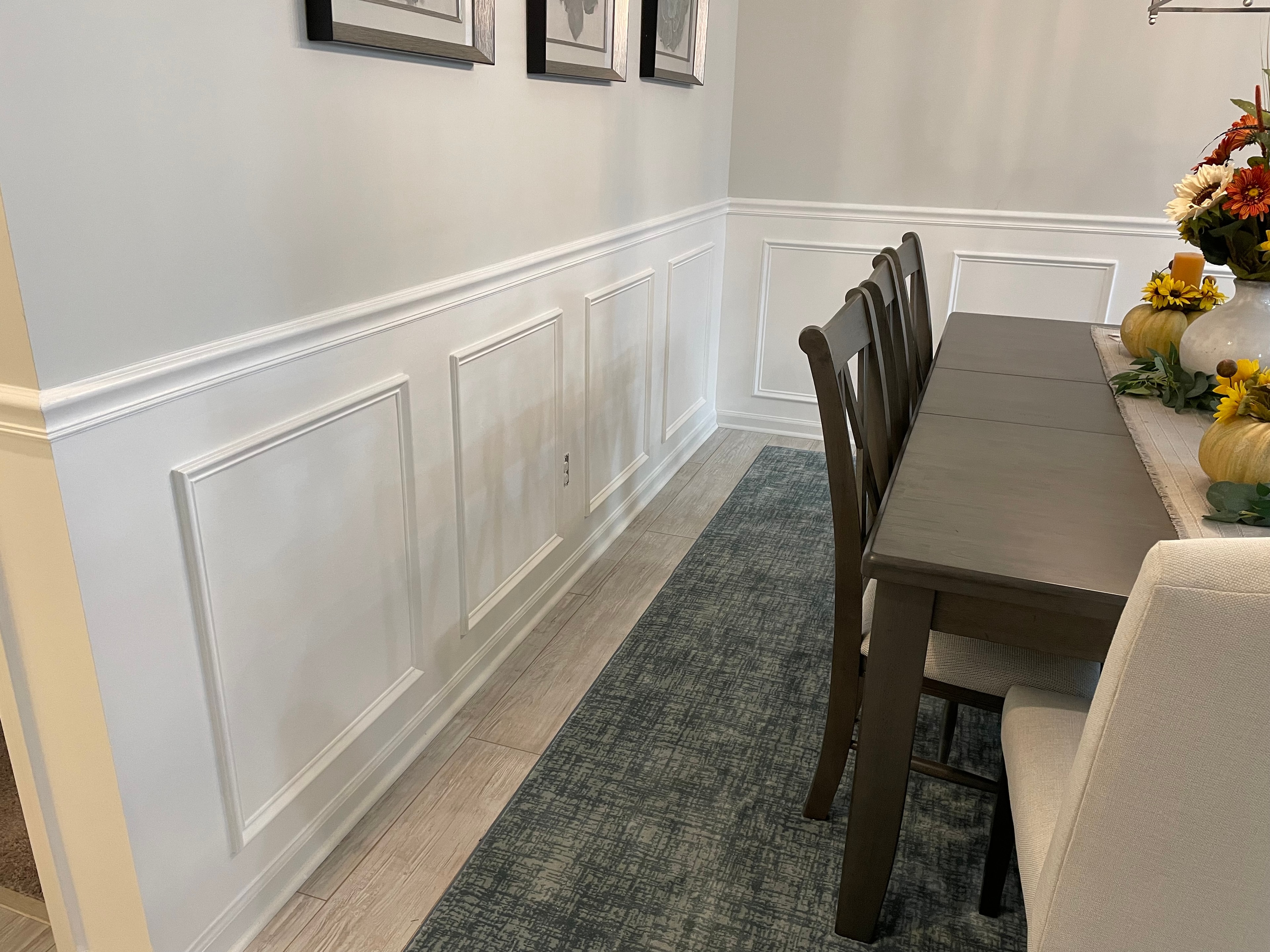 Dining room with picture frame wainscoting and wood-look tile